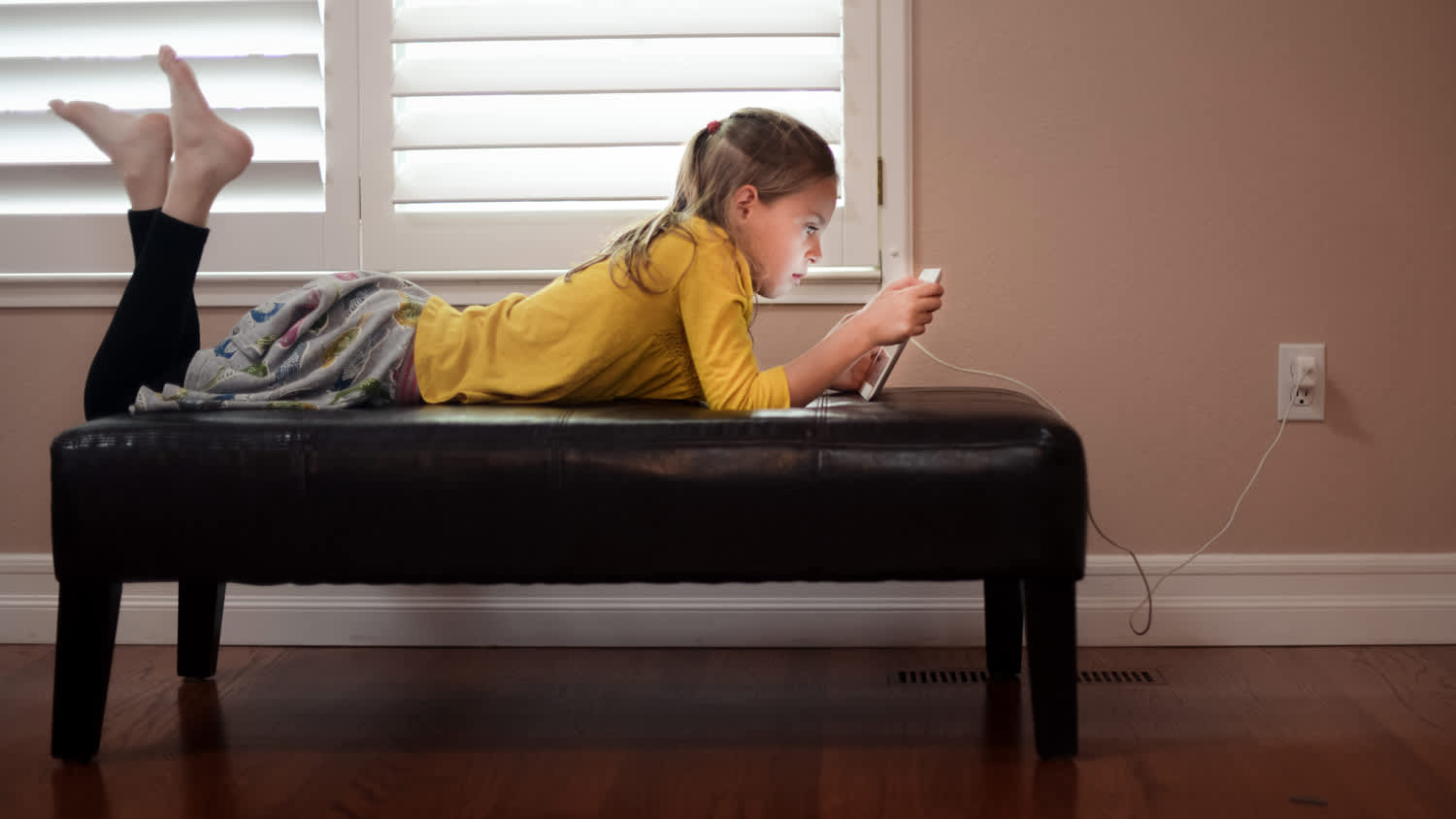 Girl using and charging tablet.