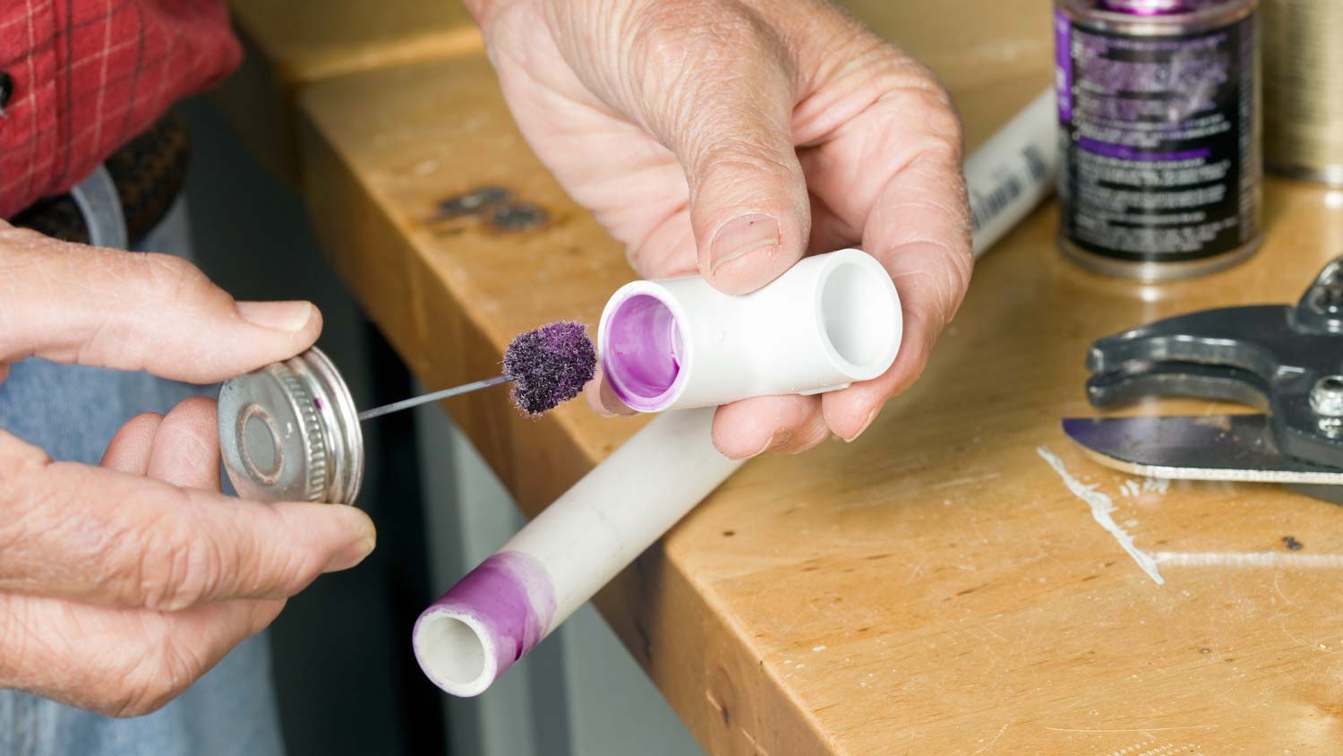 A person applying primer on PVC pipes