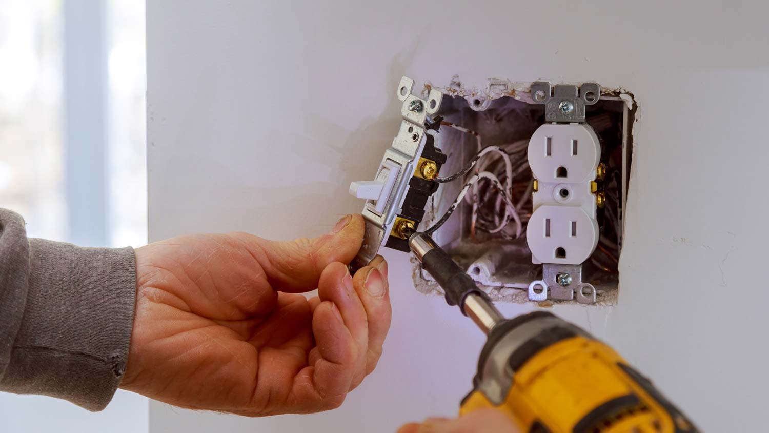 A person installing a light switch