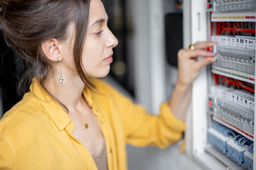 Woman checking breakers in a circuit breaker box