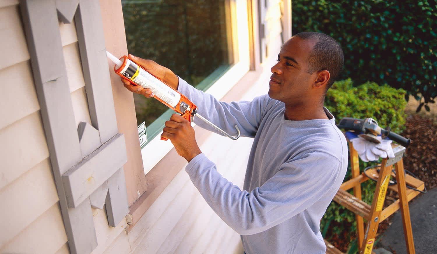 Man caulk cracks around a house window