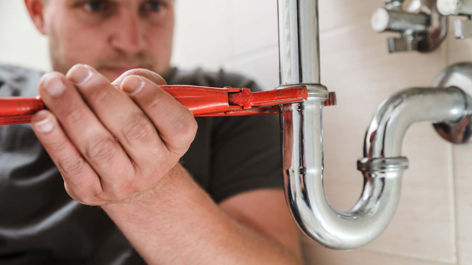 Plumber at work on sink pipe.