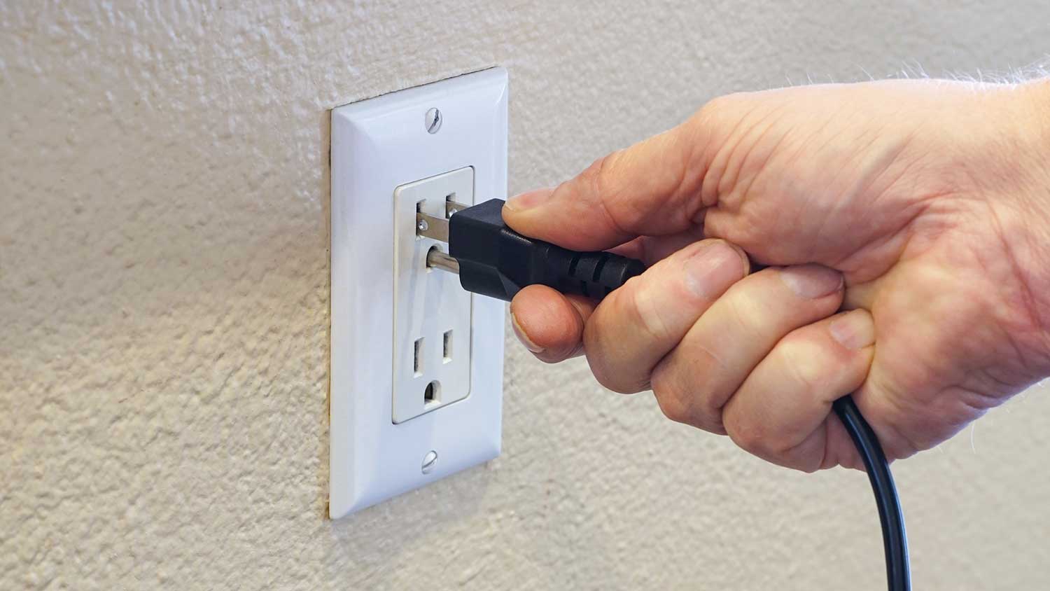 Hand plugging power cord into power outlet