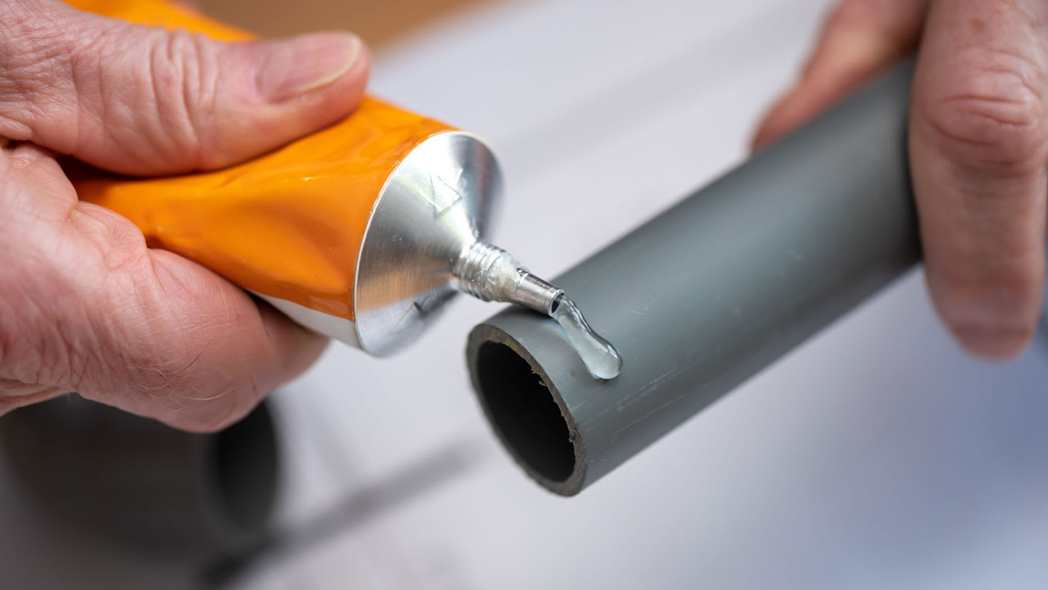 Close-up of a plumber applying glue on PVC pipes