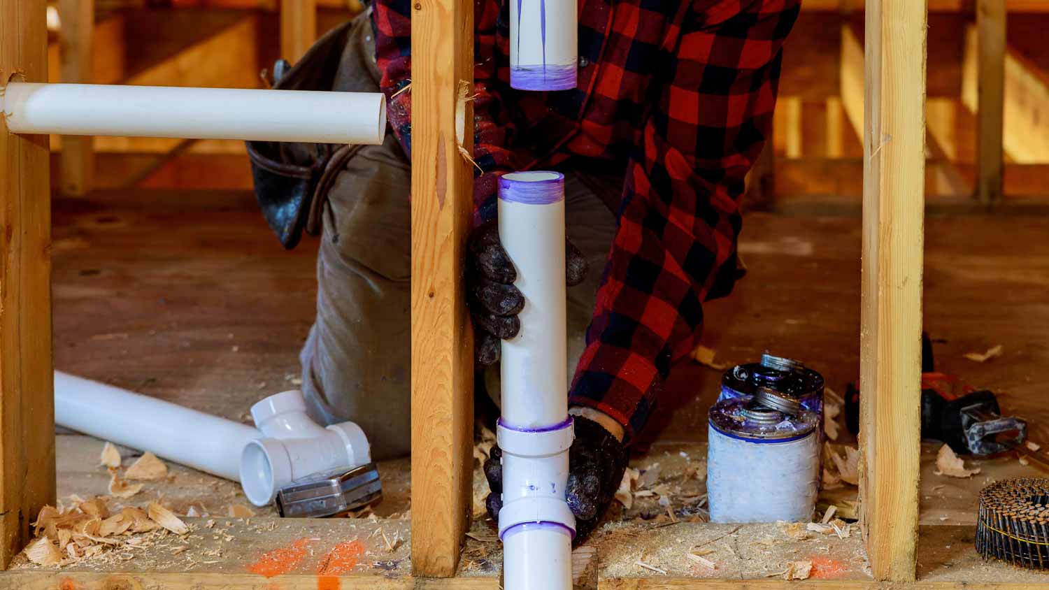 A plumber connecting PVC pipes together in a construction site