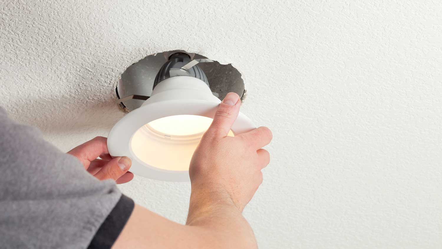 Handyman installing light fixture on the ceiling