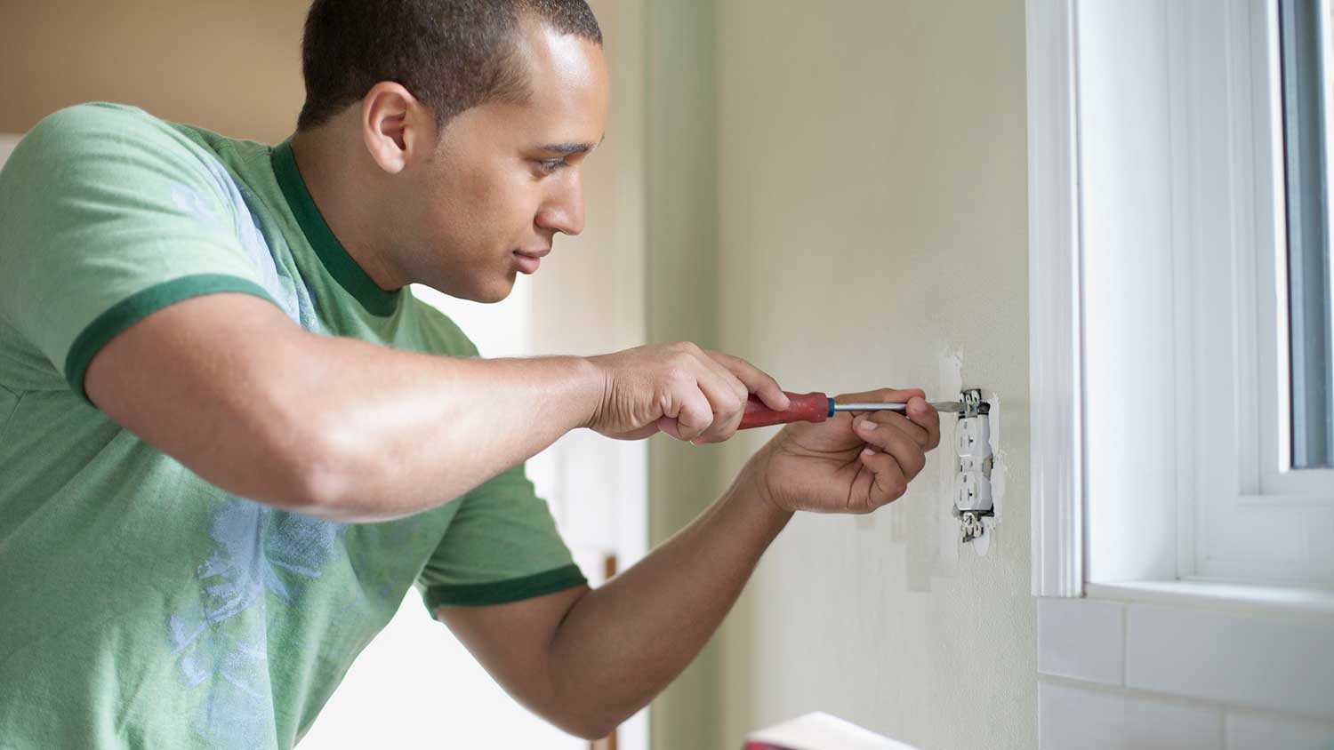 Man attaching electrical outlet to the kitchen wall