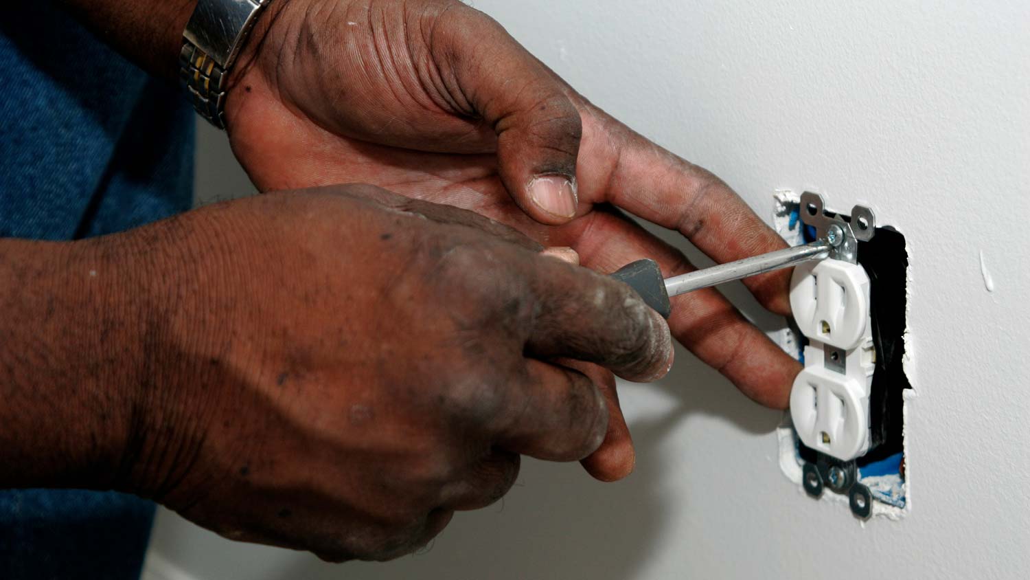 Close-up of a person repairing an electrical outlet