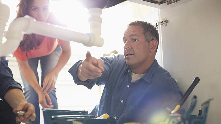 Plumber explaining water pipe problem to homeowner