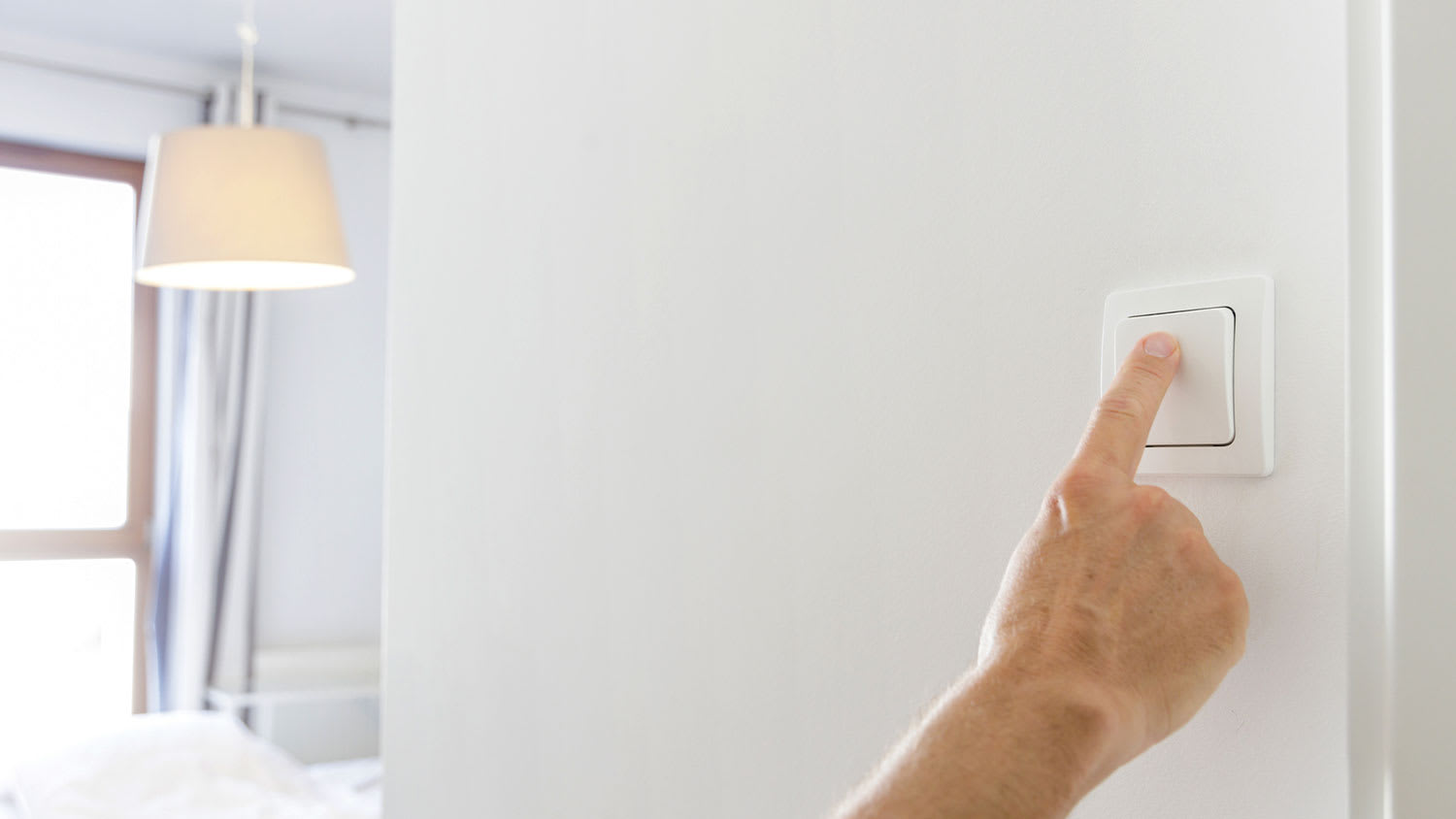Hand pressing light switch to turn lights on