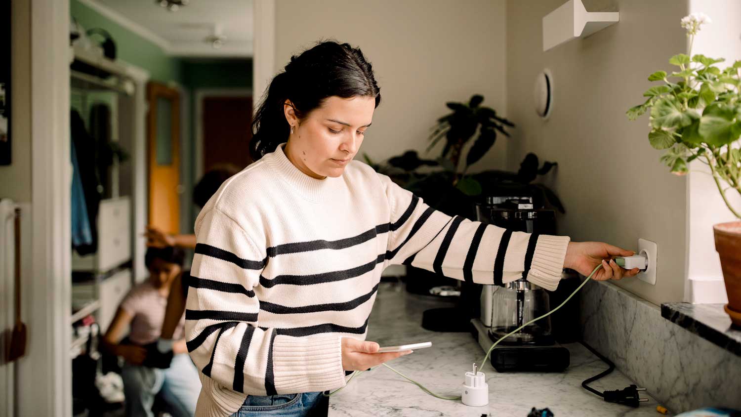 Woman plugging in phone charger in the outlet