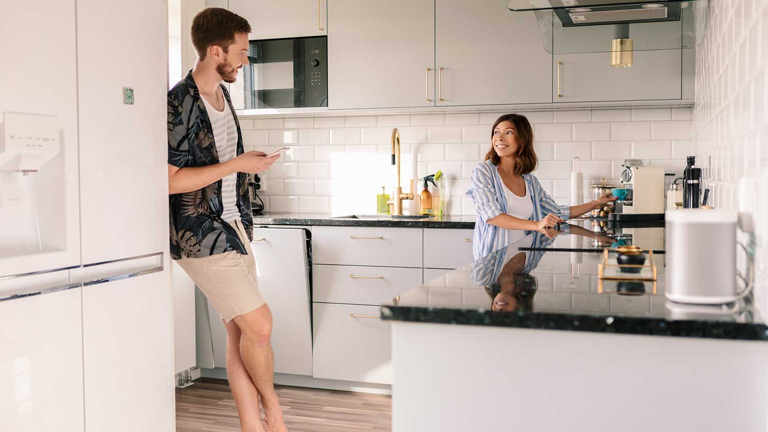 Woman chatting with a friend and making coffee in the kitchen