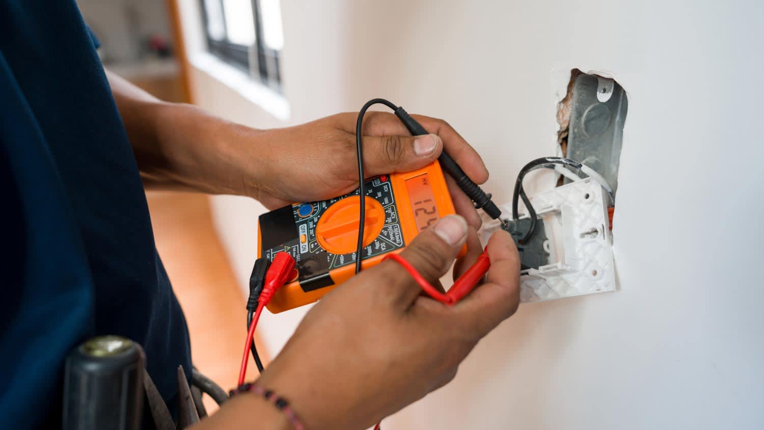 An electrician checking the voltage of an outlet with a multimeter