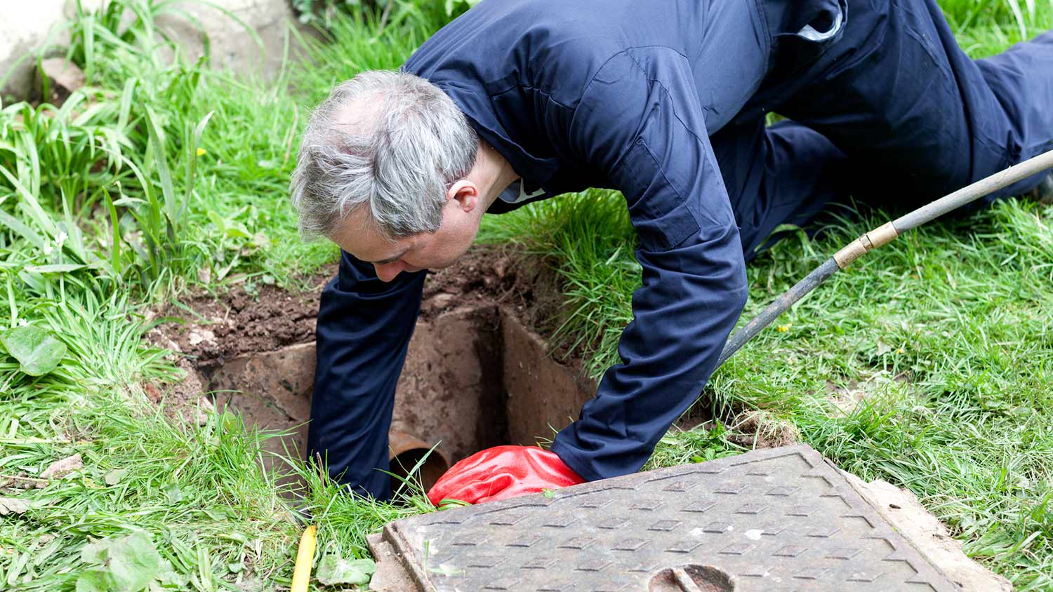 Plumber checks sewer drain outside of house