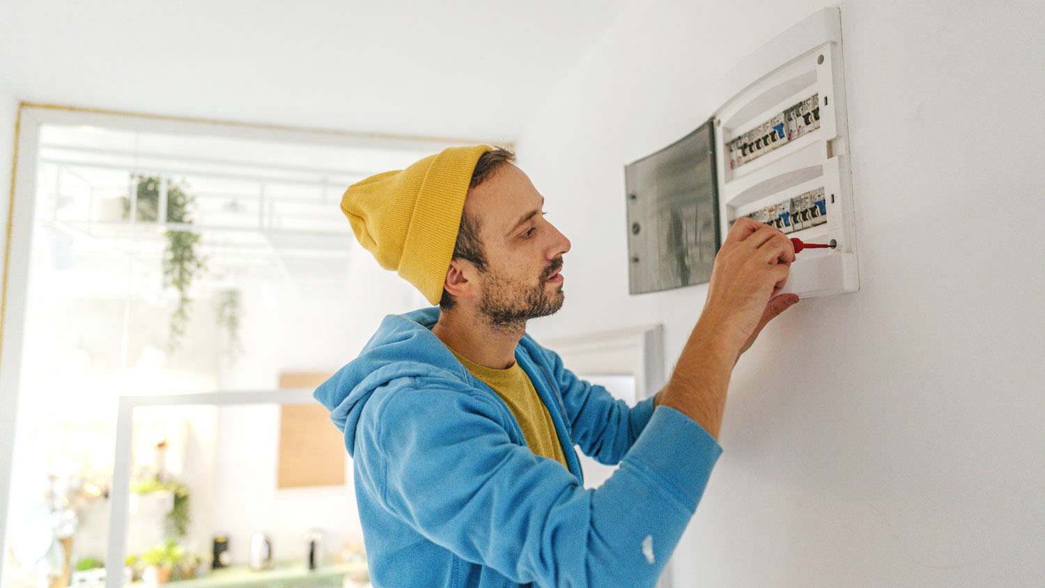 man testing fuse box in house