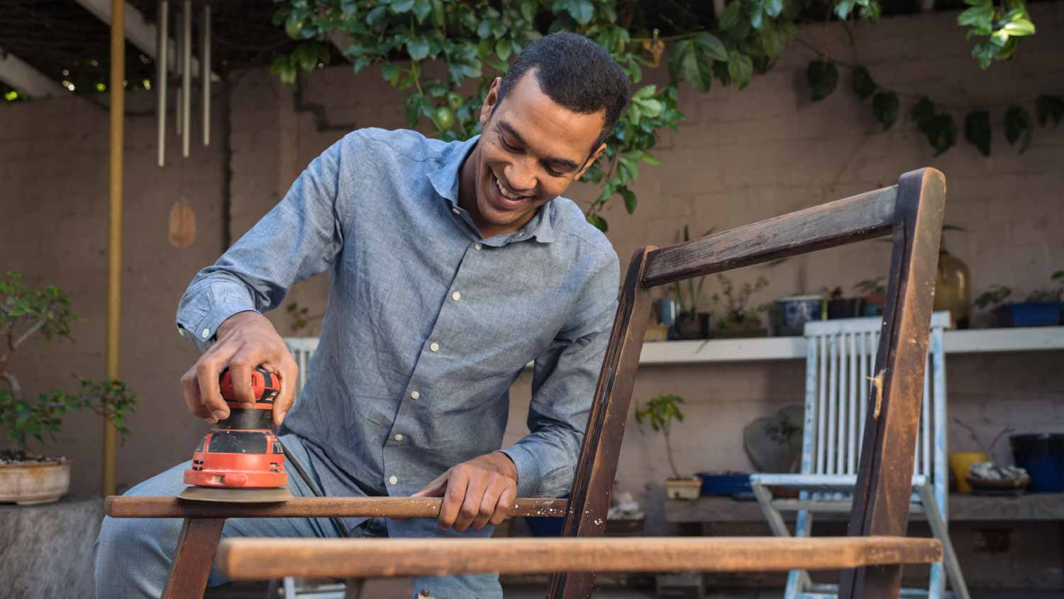 man sanding a chair outside