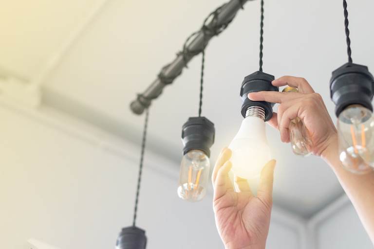 hand screwing in led lightbulbs in hanging lights