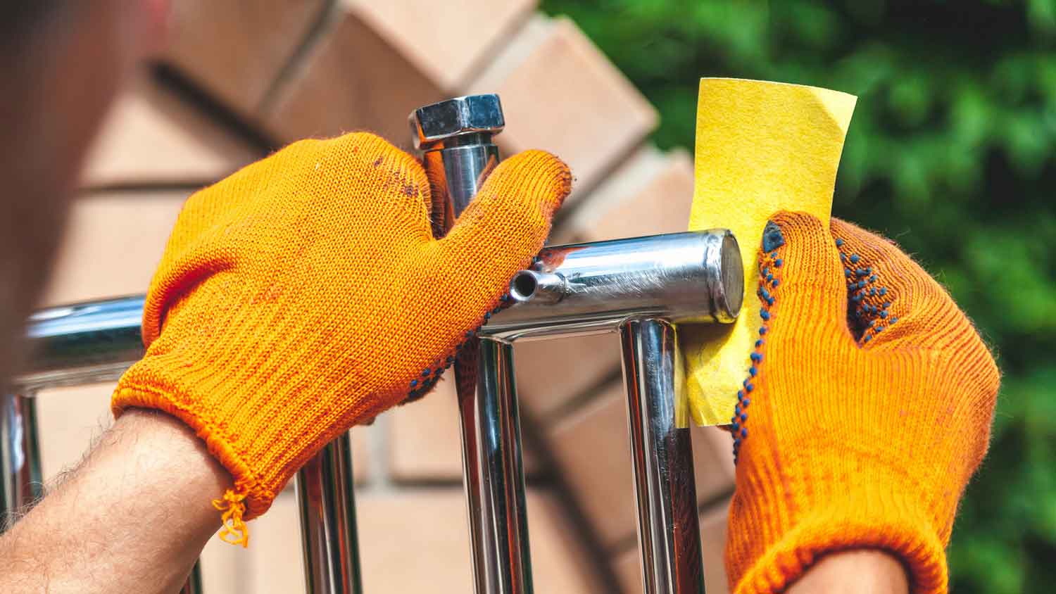 A person sanding a stainless steel towel rail