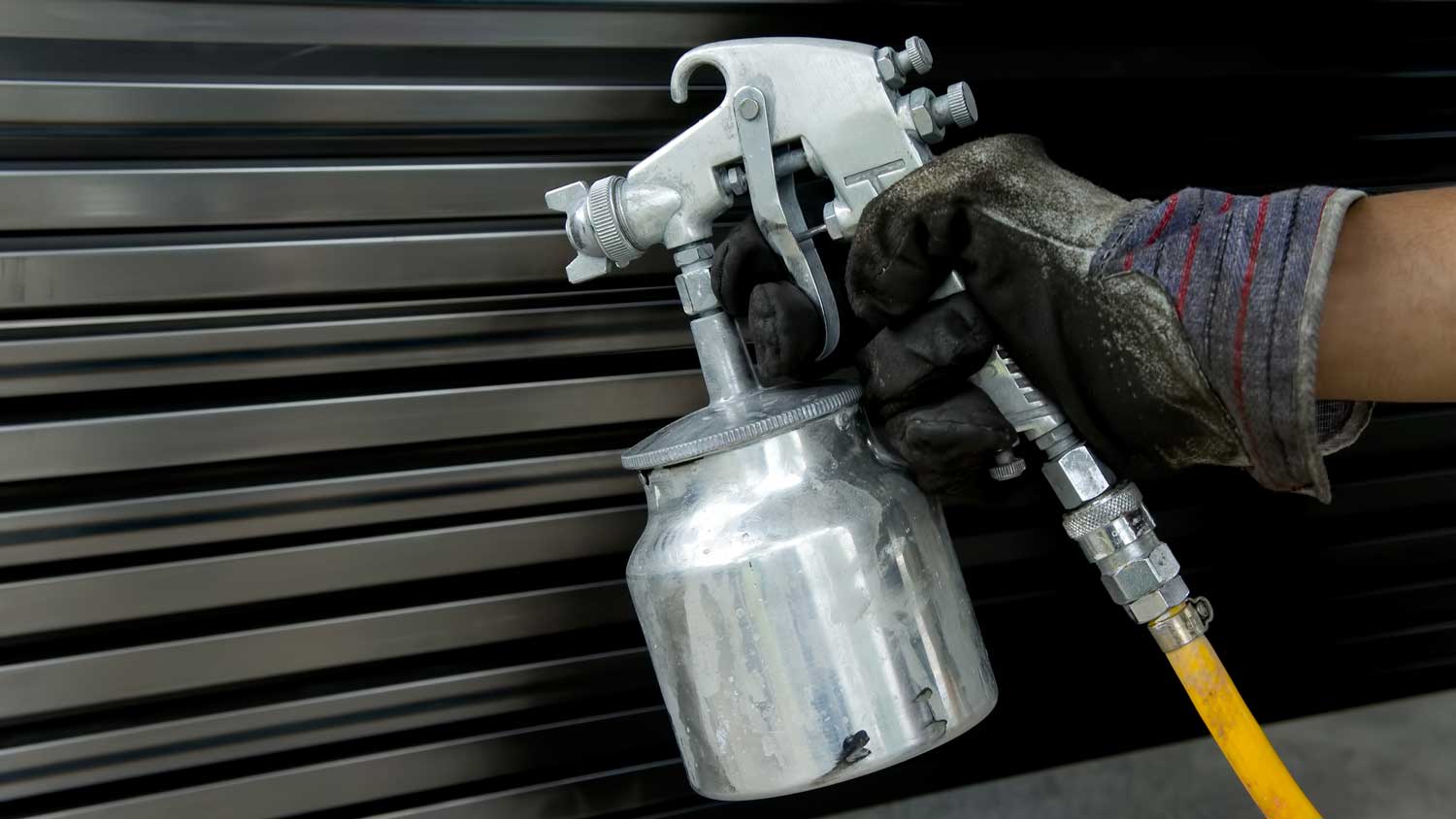 Close-up of a person spray painting a stainless steel door