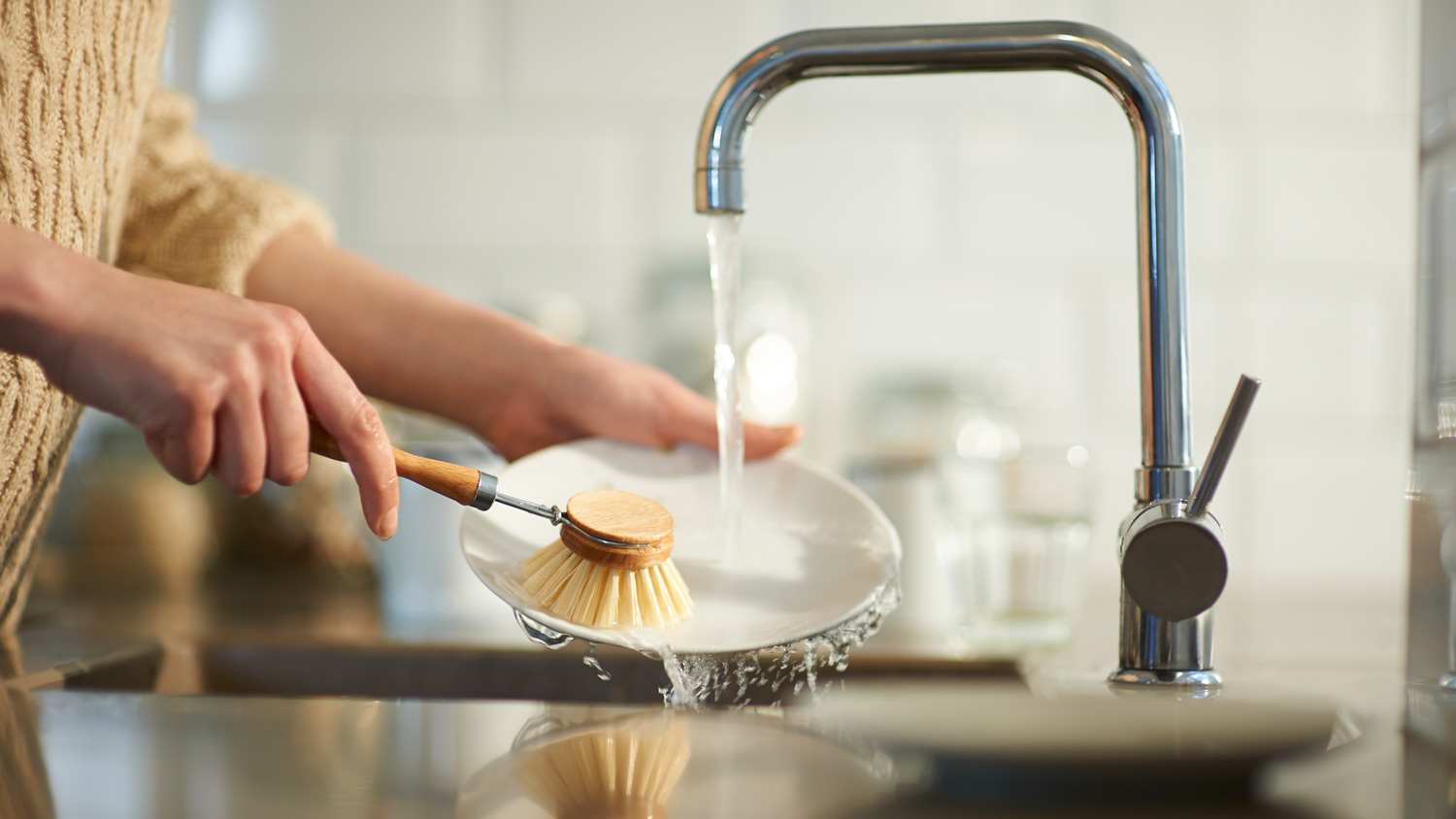 A woman cleaning a dish using a brush