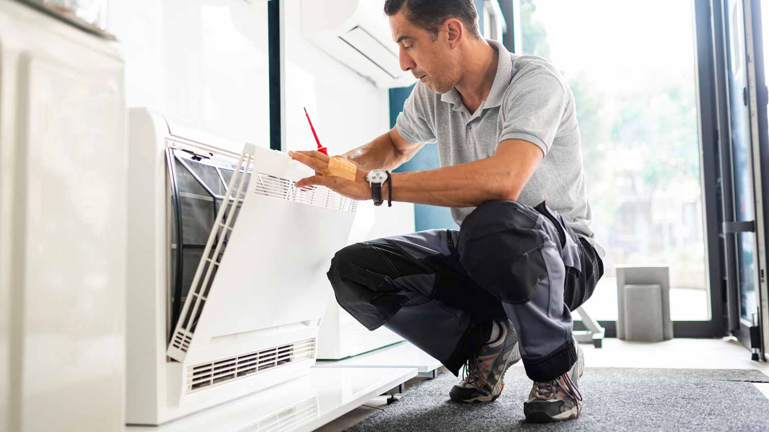 A man checking a floor mounted air conditioner