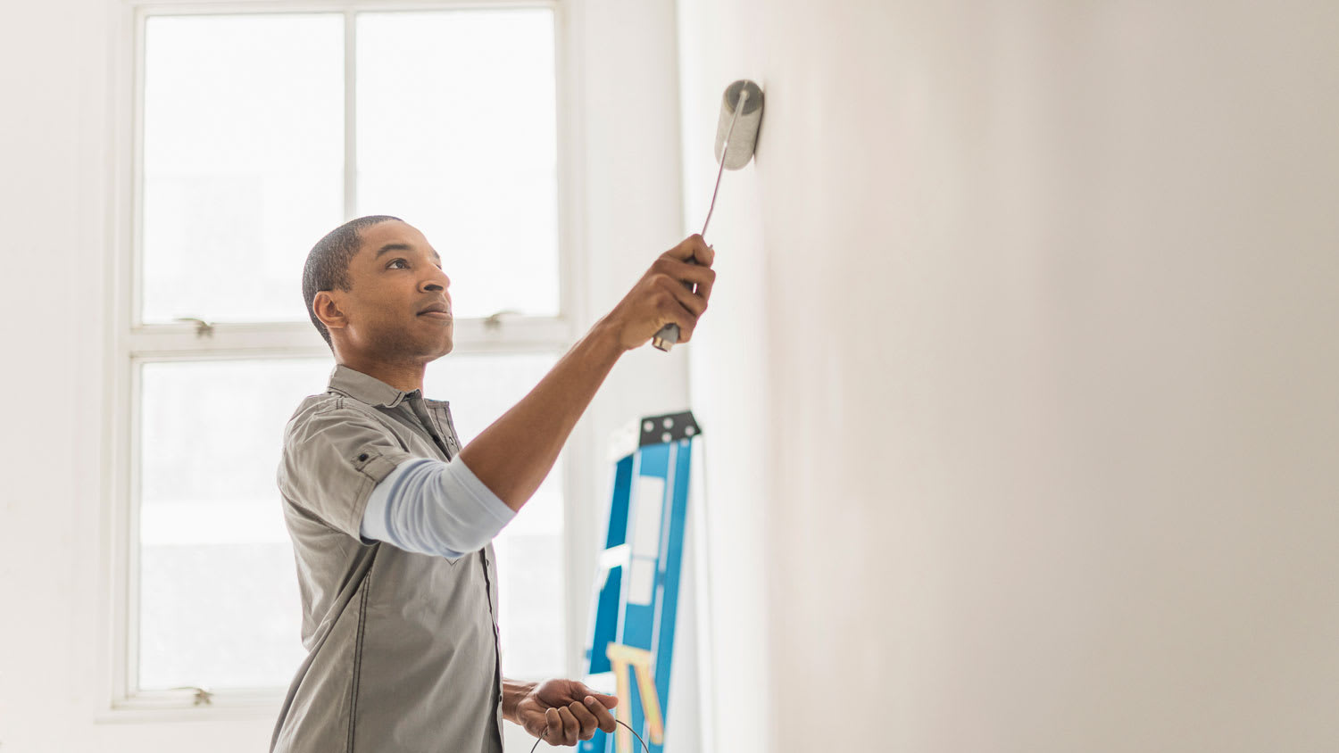 A man painting with primer a wall