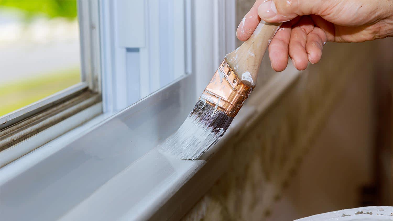man painting the edge of the window trim