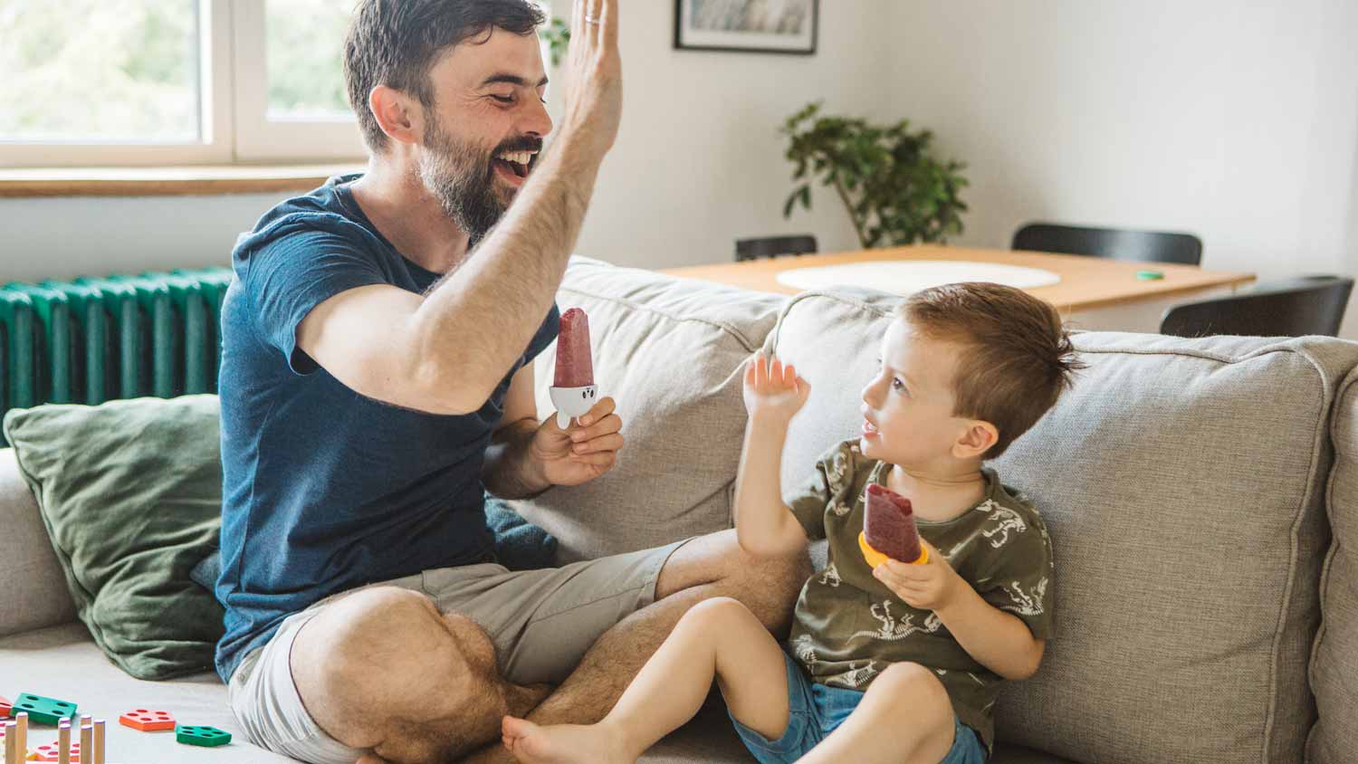 A father and his son having popsicles in their living room