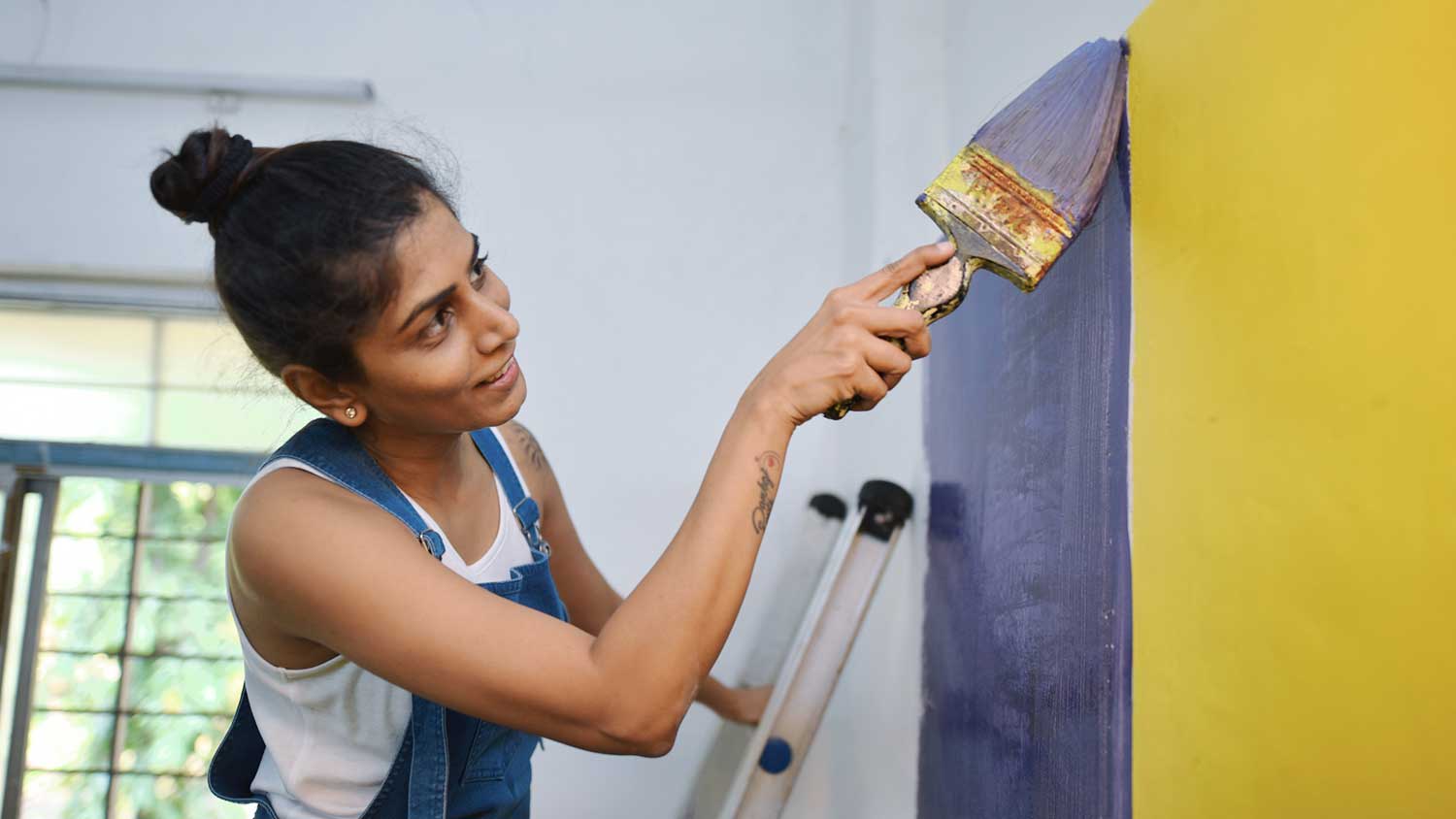 Woman using brush to paint a wall