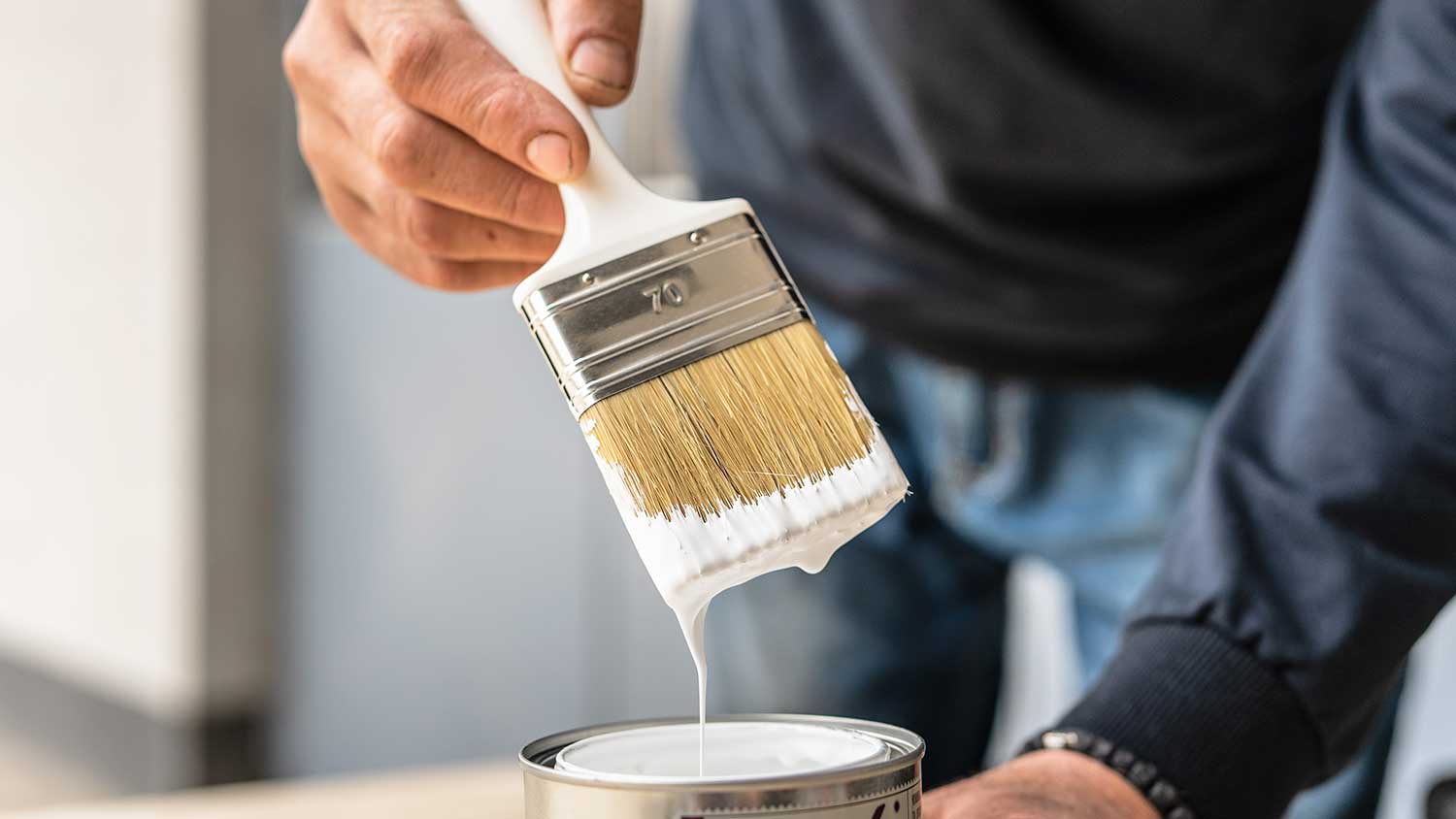 Man removing excess paint from brush