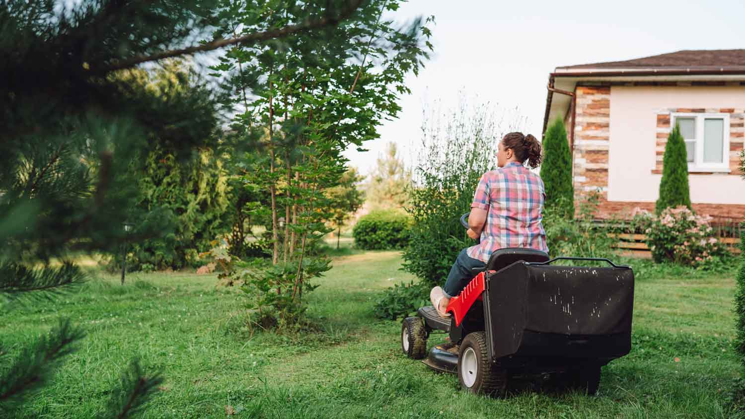 A woman operating a lawn mower in her garden