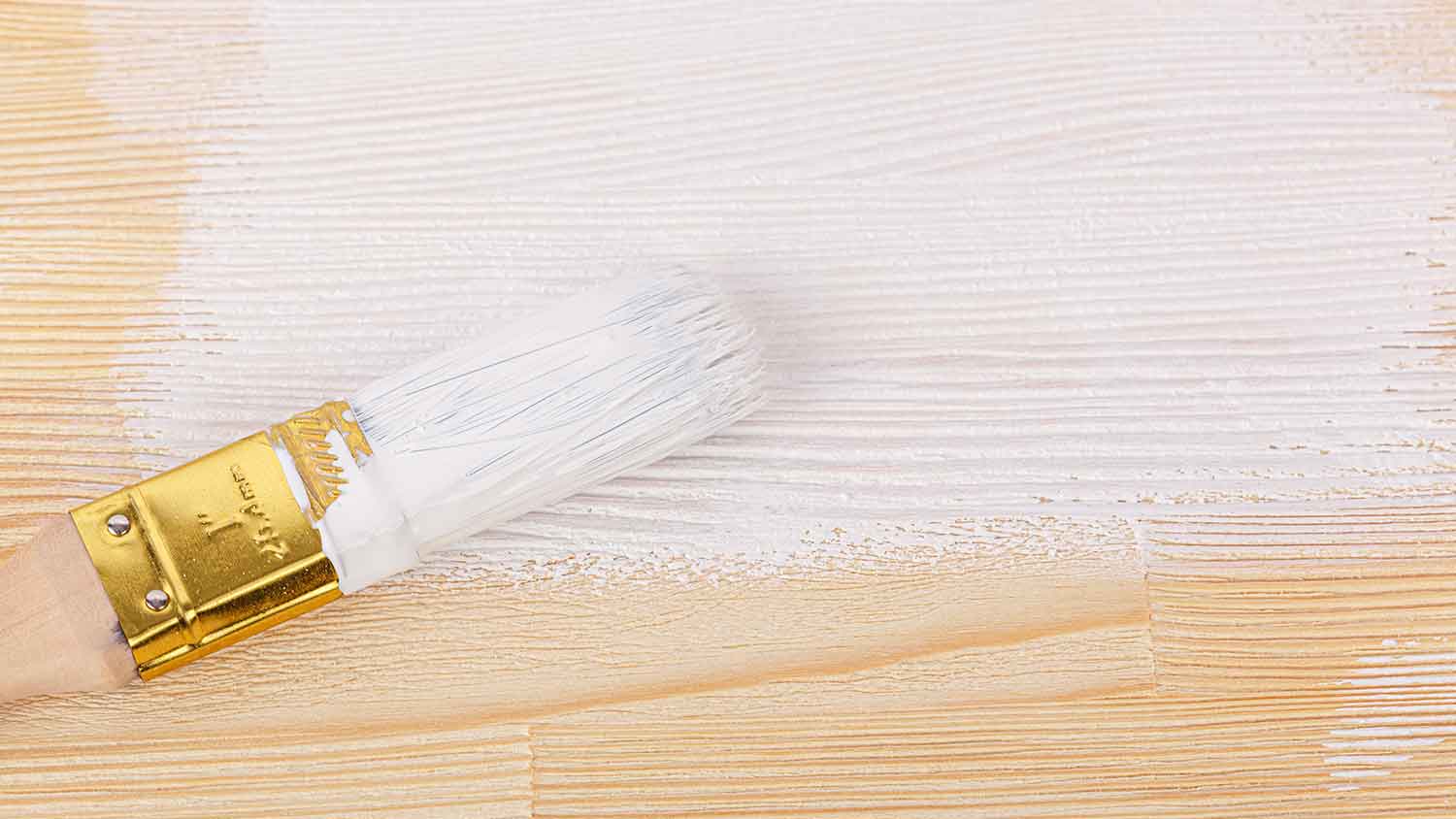 Brush with white paint on a wooden surface