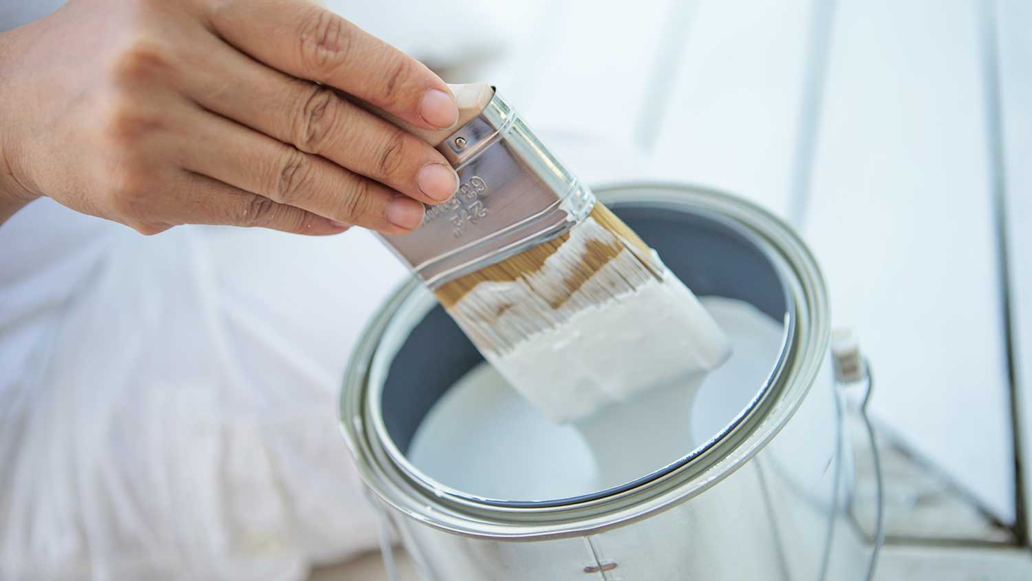 Dipping brush into a paint can