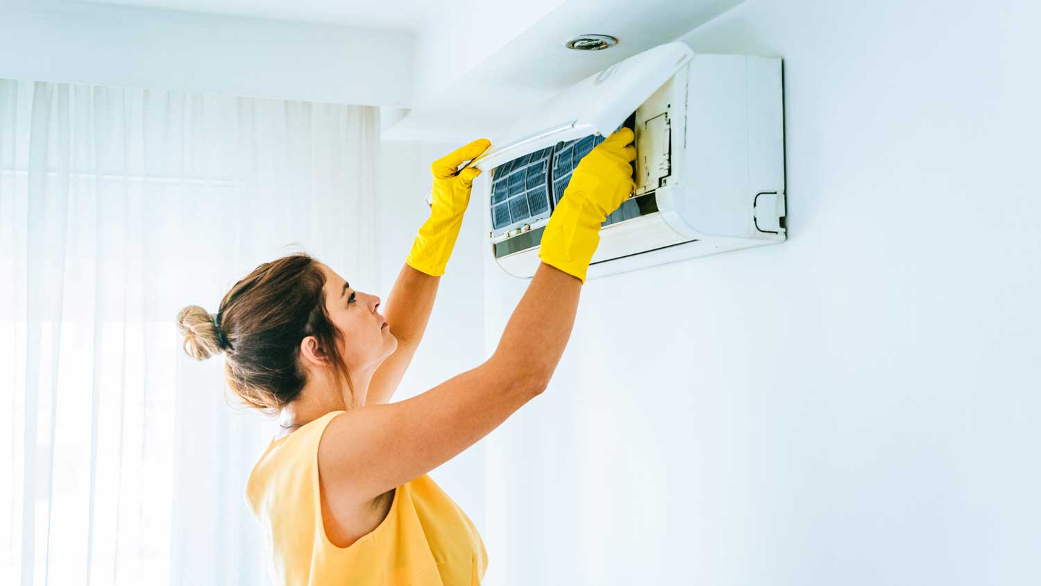 A woman removing the filter from an AC