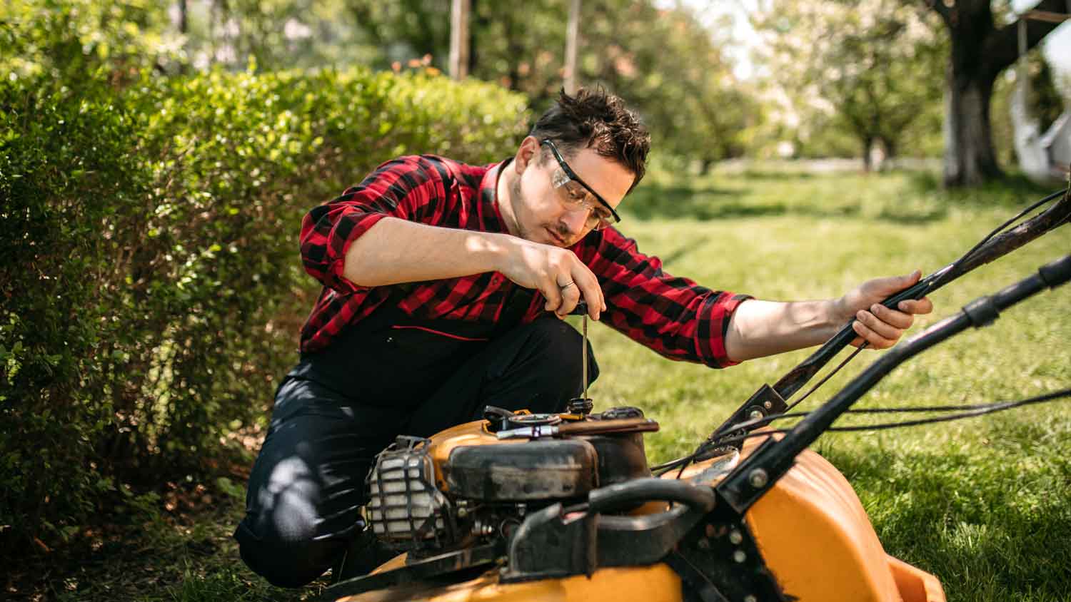 A young man fixing the lawn mower