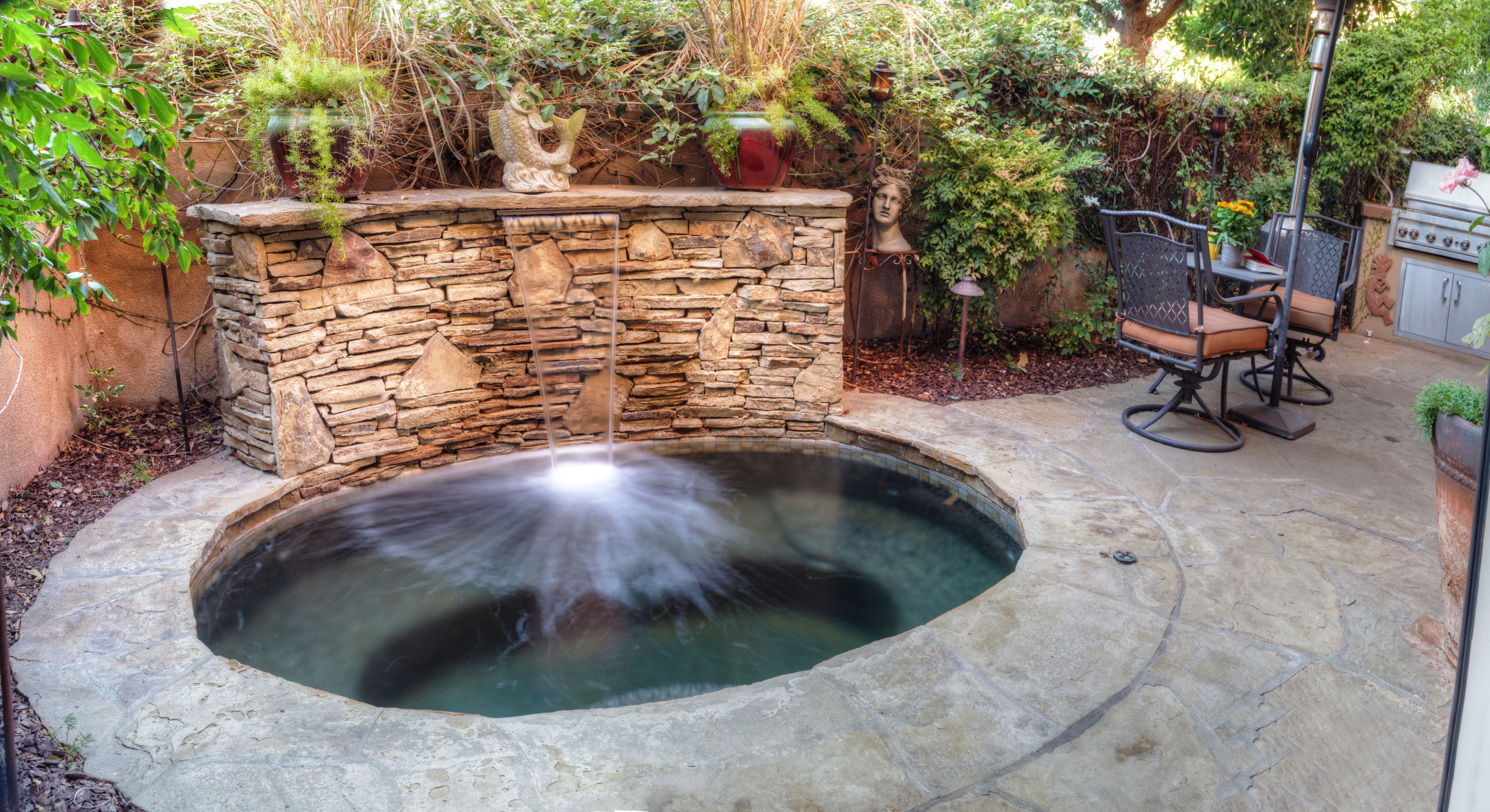 An inground hot tub with a stone waterfall feature