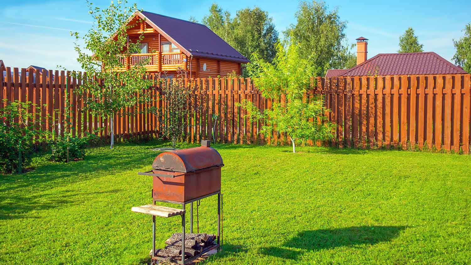 House backyard with a wooden box fence and a grill