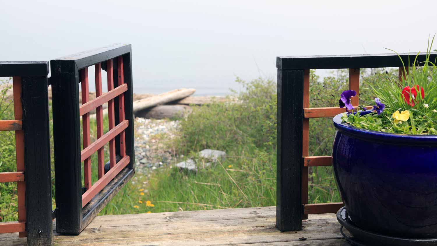 A wooden deck with a gate leading to the beach