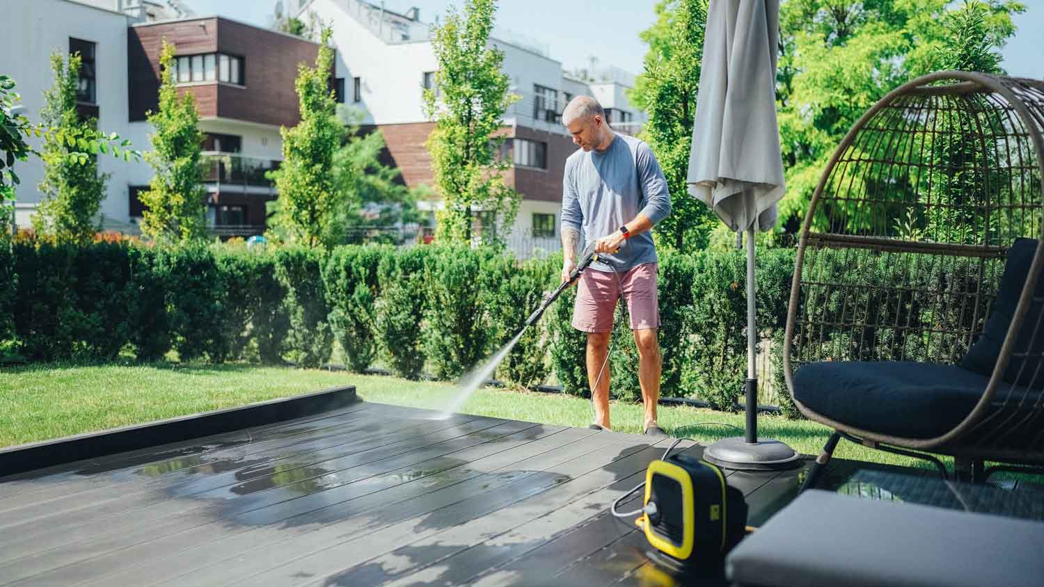 A man power washing a wooden deck