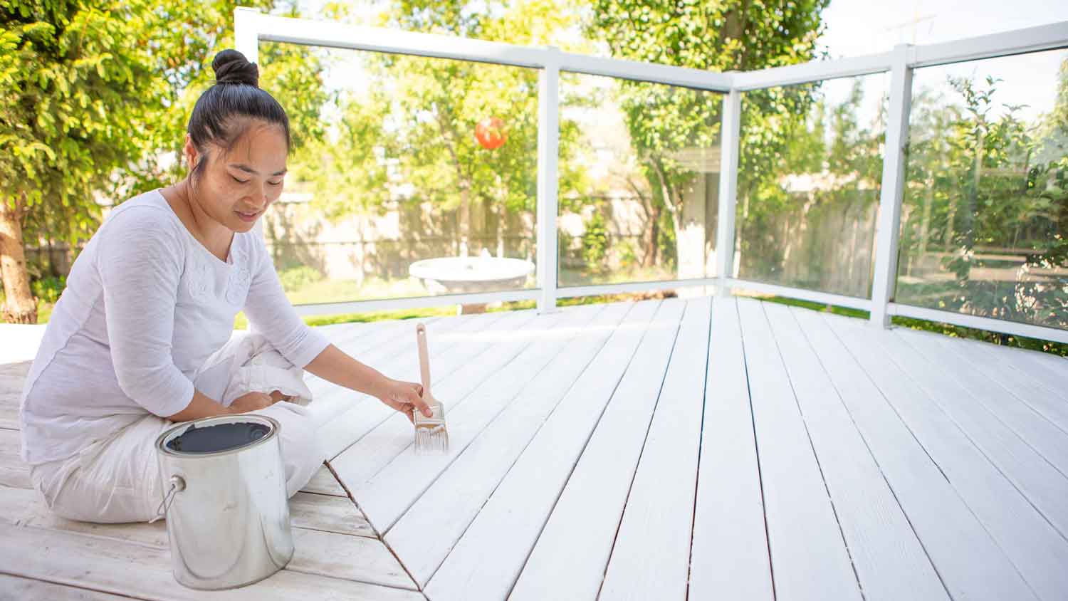 A woman painting a wooden deck with a brush