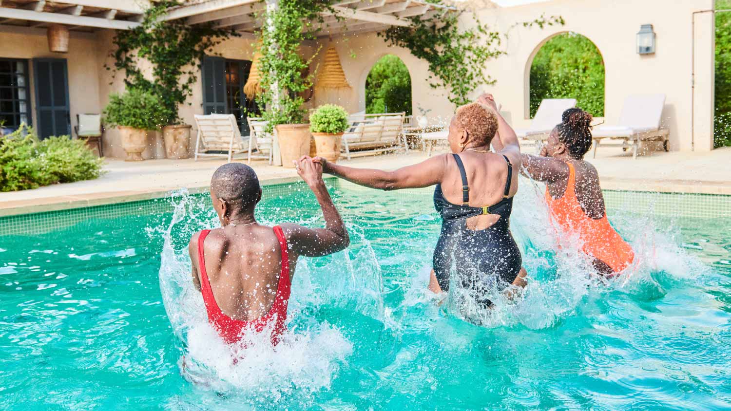 women jumping into a villa swimming pool