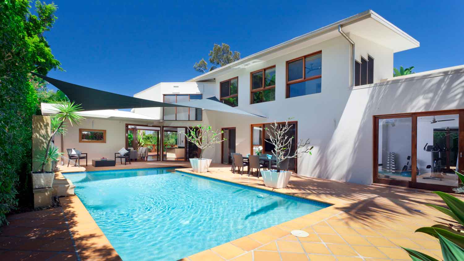 A pool in the backyard of a two-story house