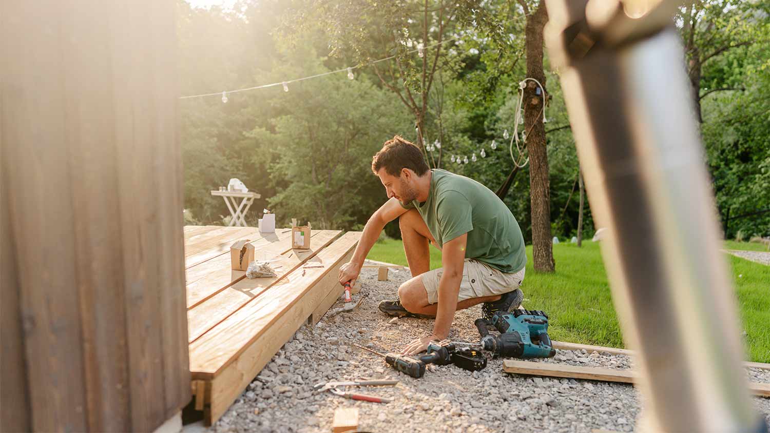 man attaching deck boards to house