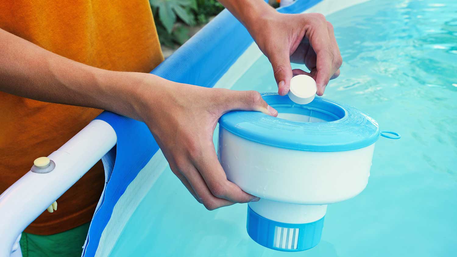 Worker adding chlorine tablet to a floating chlorine dispenser