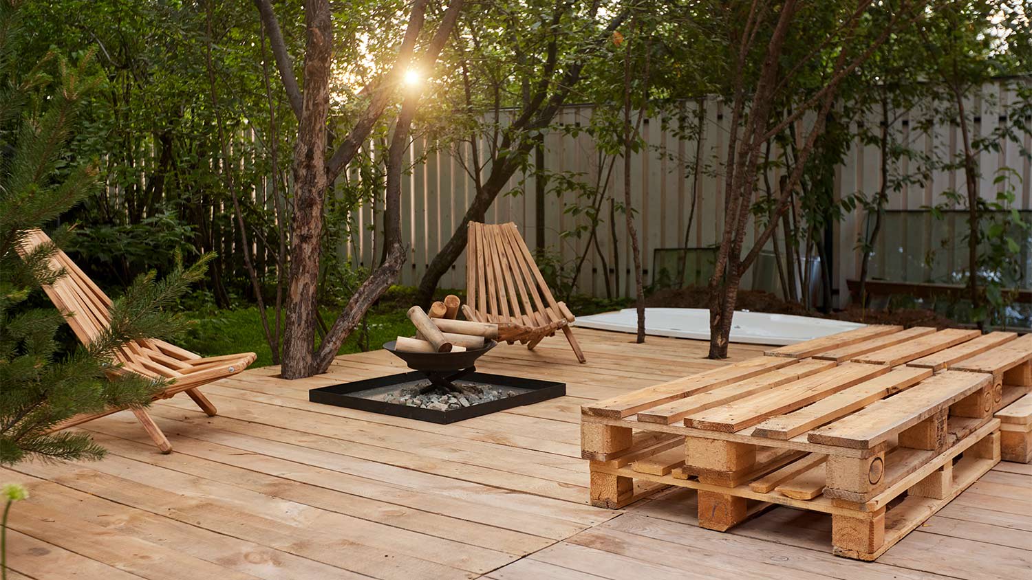 Fire place on the wooden veranda next to chairs in garden