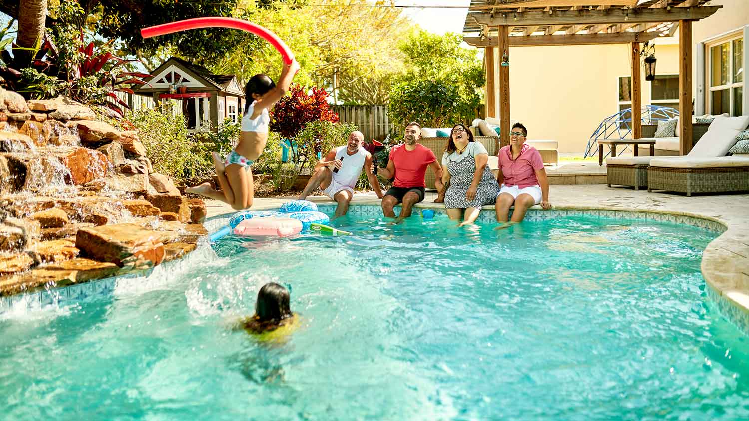 Family sitting poolside watching the children play