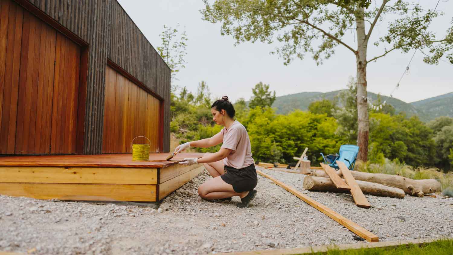 A woman applying paint strip to a deck