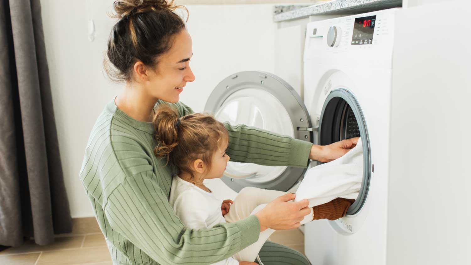 Mother and girl loading washing machine
