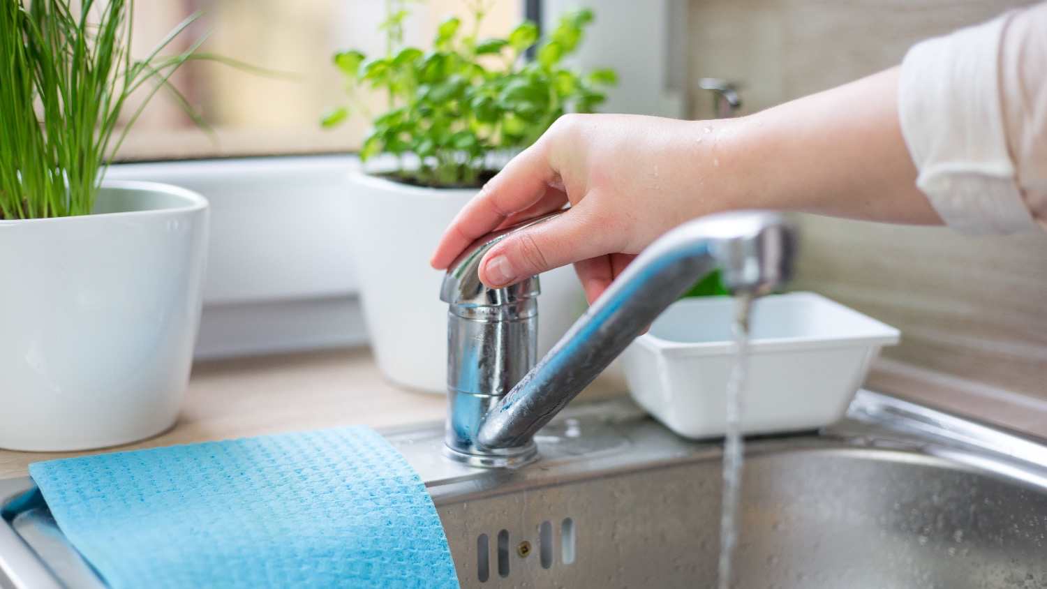 woman in kitchen with faucet running