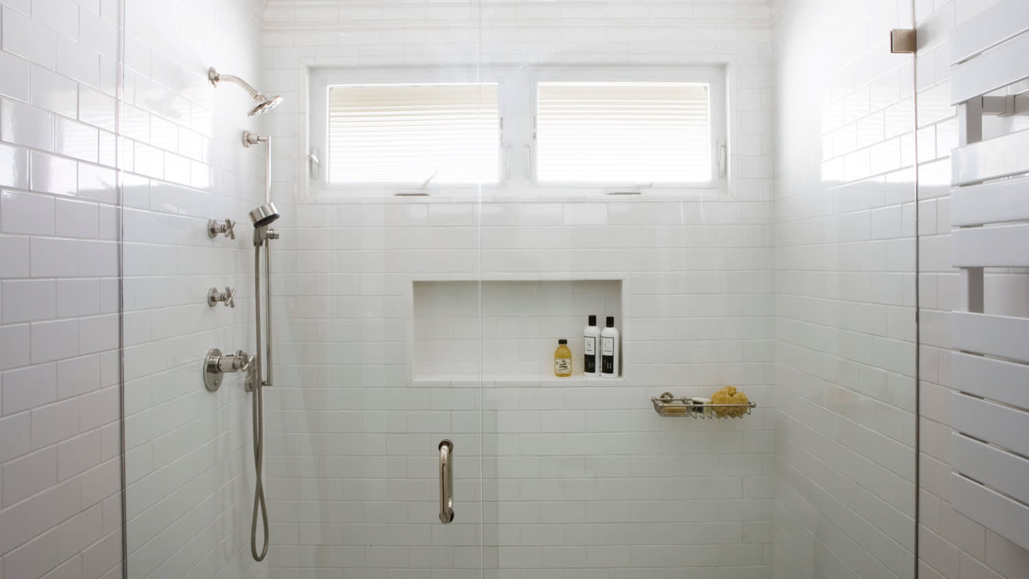 A bright white tiled bathroom with a shower
